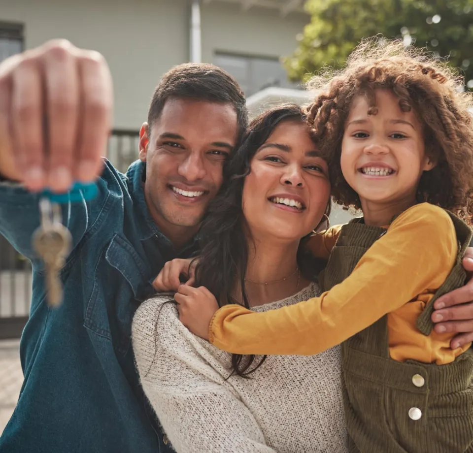 Família sorridente mostrando a chave da casa nova